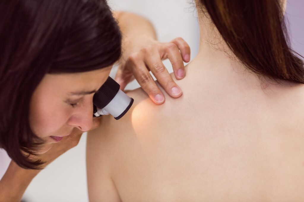 dermatologist examining skin patient with dermatoscope